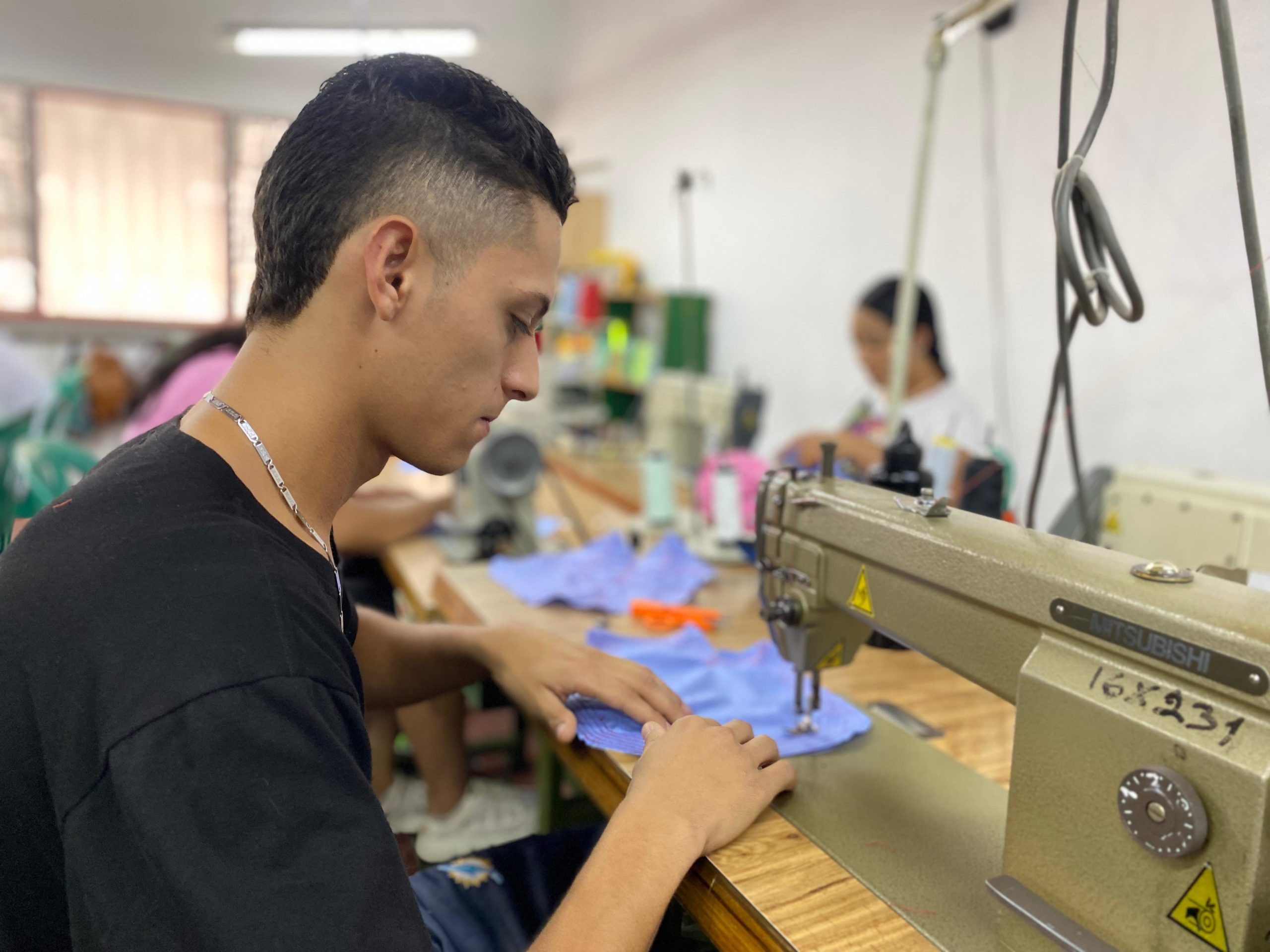 Joven realizando un trabajo de practica en una maquina de coser.