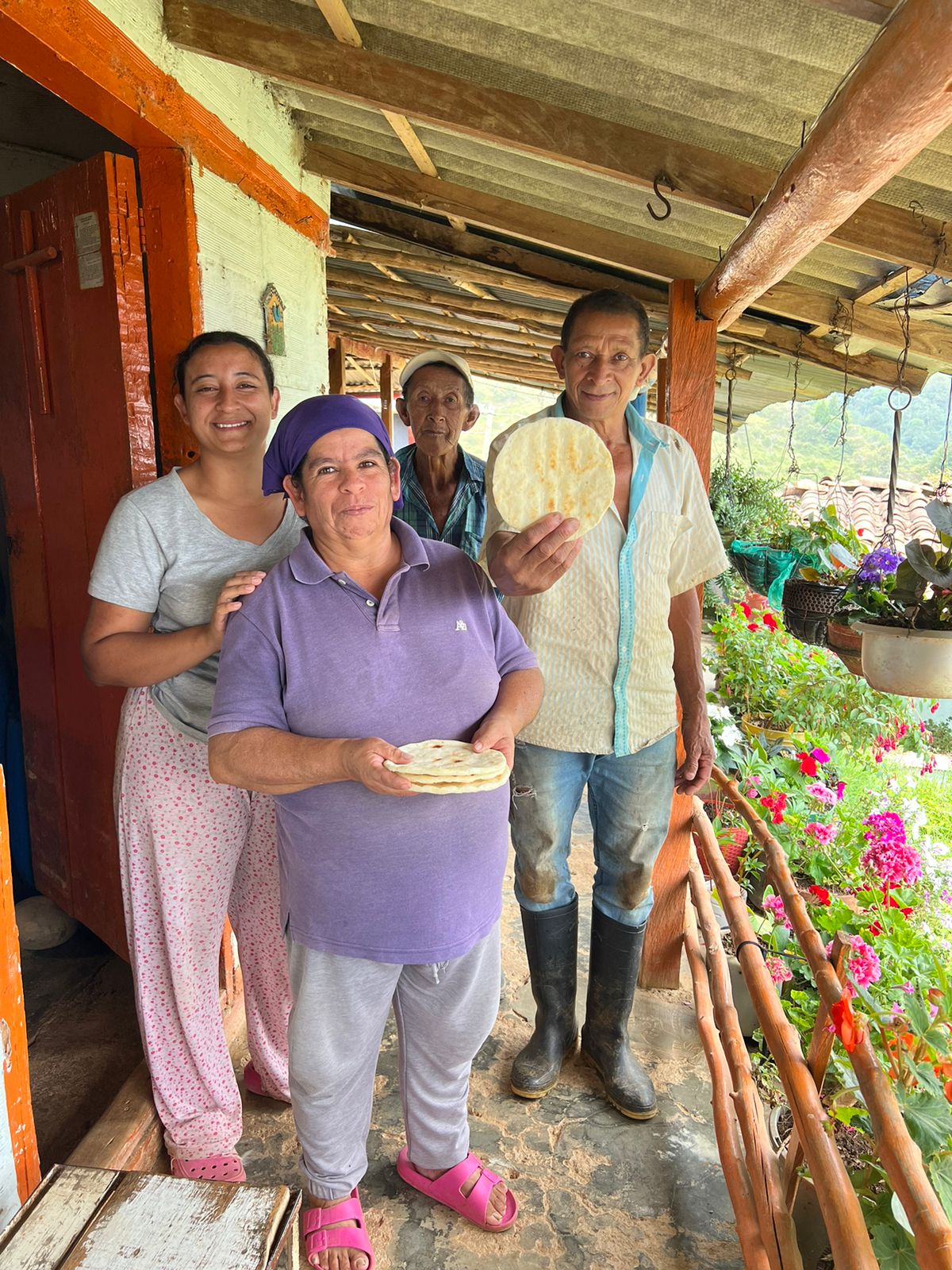 Cuatro personas sonrientes sosteniendo un preciado y muy importante alimento (arepa)