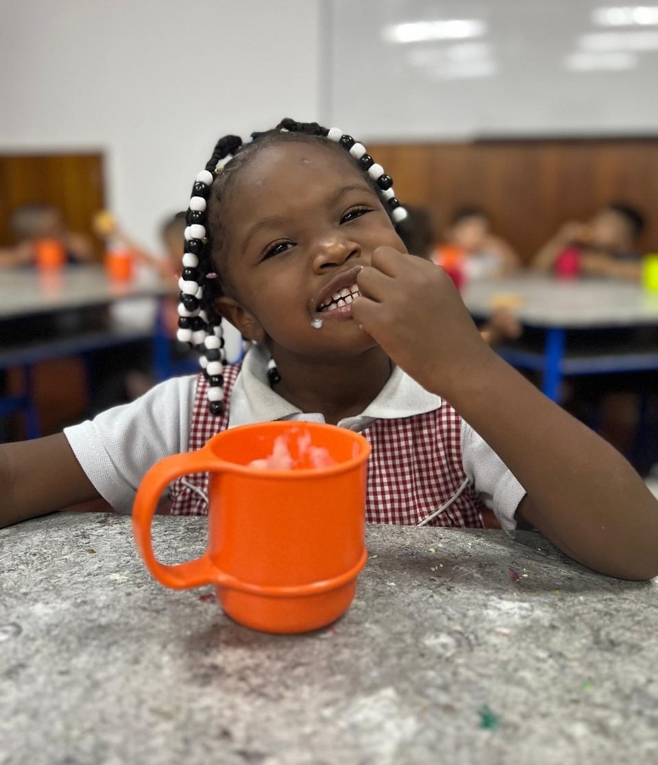 Cuatro niños abrazados, sonrientes y saludando a la cámara.