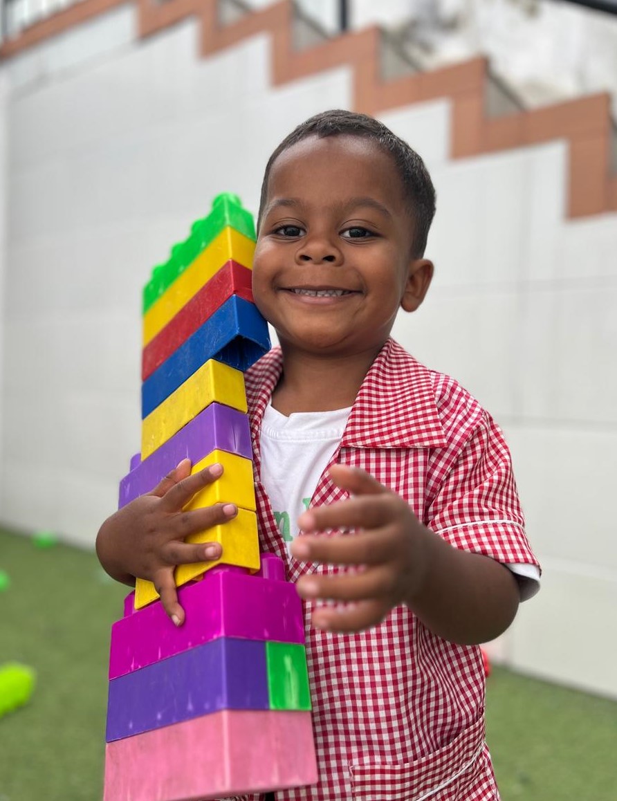 Cuatro niños abrazados, sonrientes y saludando a la cámara.