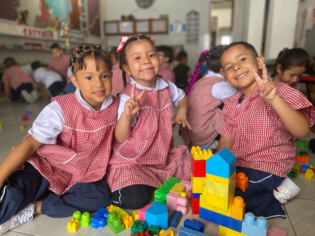 Fotografía de niños alrededor de una mesa sonrientes