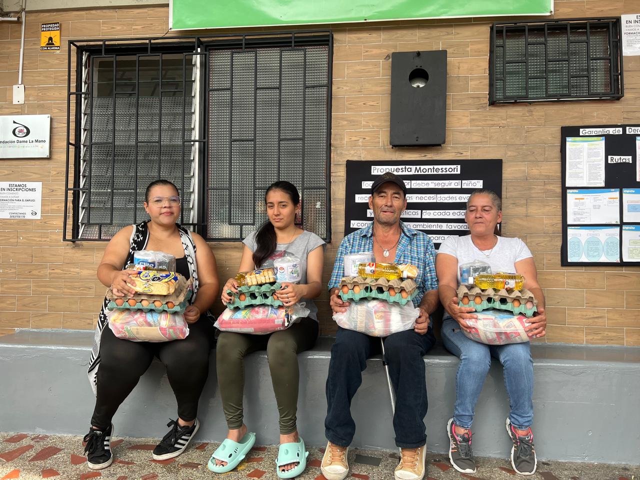 Cuatro personas sonrientes sosteniendo un preciado y muy importante alimento (arepa)